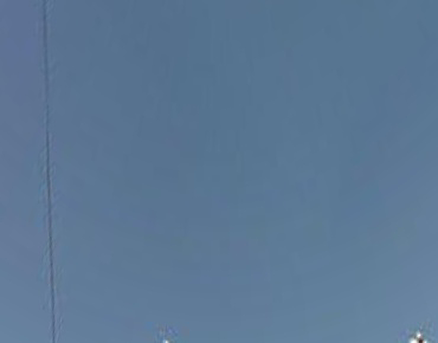 An abstract photograph of cloudless blue sky. A power line cuts vertically across the left side of the image, and a couple of street lights just barely poke into the bottom of the frame.