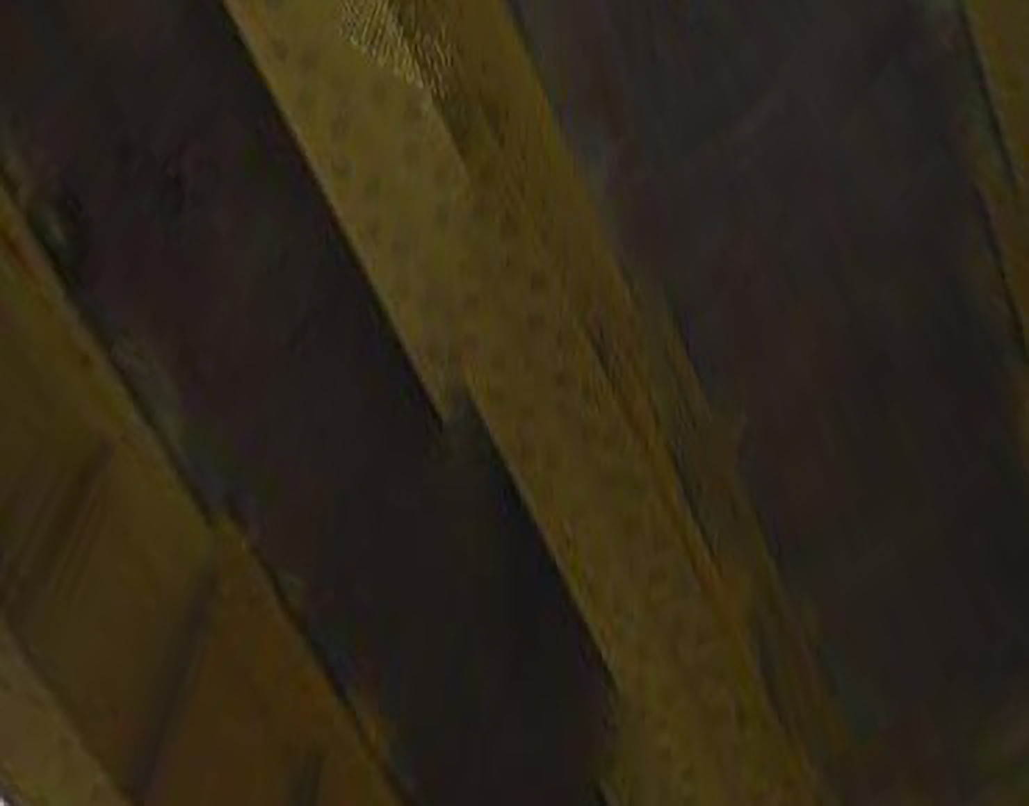 An abstract photograph of the underside of a yellow bridge, built out of riveted steel.