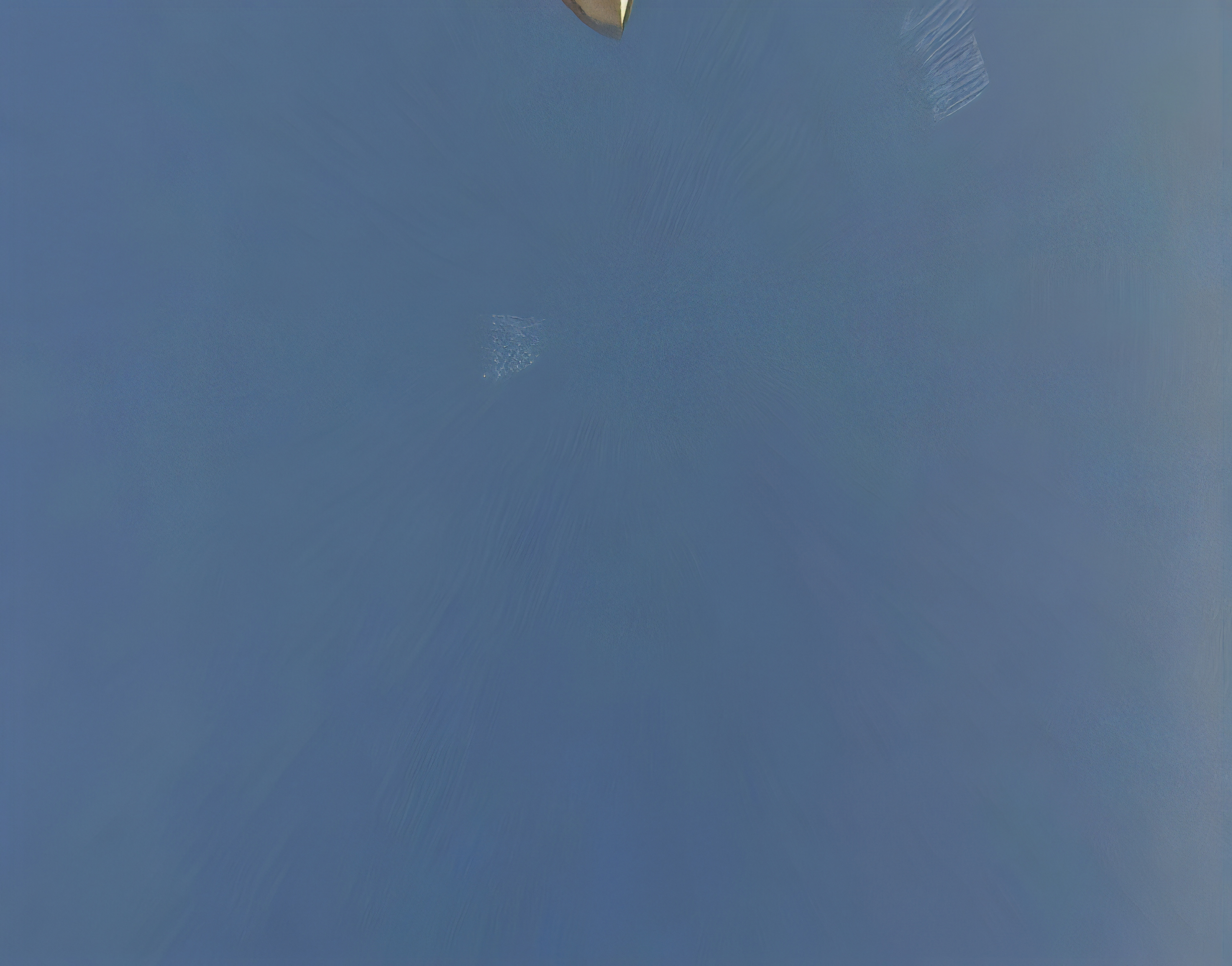 An abstract photograph of a cloudless blue sky. The tip of a street light pokes into the top of the frame.